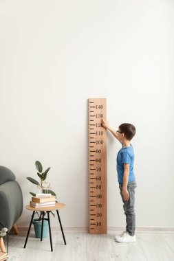 Evde boyunu ölçen küçük bir çocuk.
