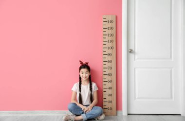 Renk duvarının yanında boyunu ölçen küçük kız