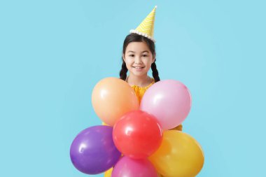 Balonlu şirin küçük kız renk geçmişinde doğum gününü kutluyor.