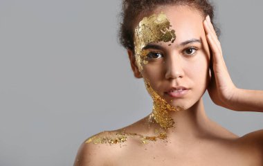 Gri arka planda altın rengi boyası olan güzel bir Afro-Amerikalı kadın.