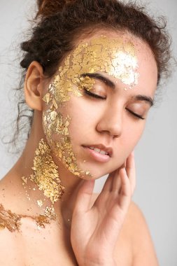 Gri arka planda altın rengi boyası olan güzel bir Afro-Amerikalı kadın.