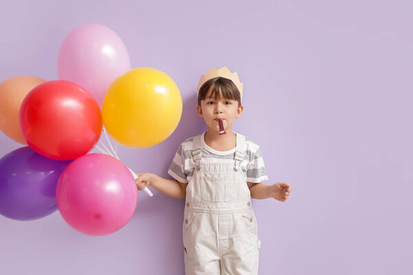 Cute little boy with balloons celebrating Birthday on color background