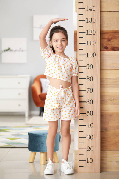 Маленькая девочка измеряет рост дома