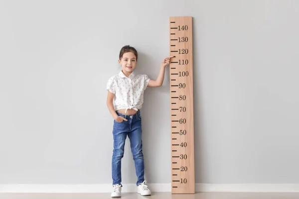 Маленькая Девочка Измеряет Высоту Возле Светлой Стены — стоковое фото