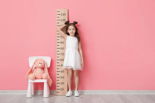 Mała Dziewczynka Mierzy Wzrost Pobliżu Ściany Kolor — Zdjęcie stockowe