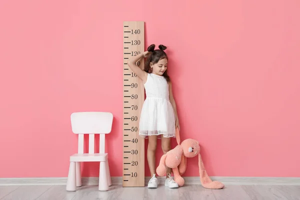 Mała Dziewczynka Mierzy Wzrost Pobliżu Ściany Kolor — Zdjęcie stockowe