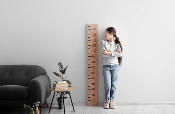 Маленькая девочка измеряет рост дома