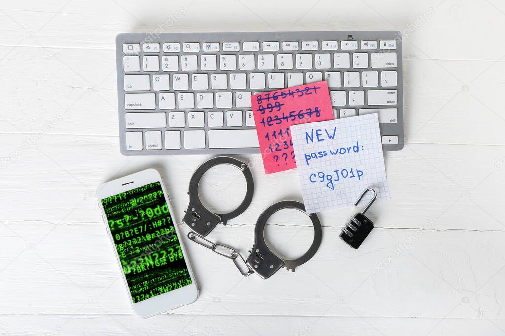 Mobile phone with computer keyboard, handcuffs and papers with passwords on table of hacker