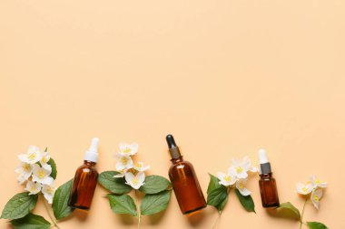 Renkli arka planda gerekli yağ ve yasemin çiçekleri şişeleri