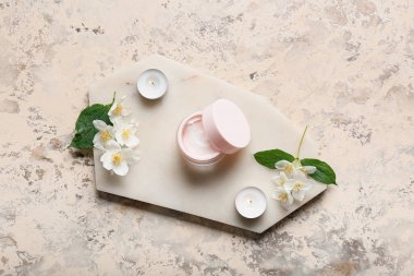 Krema kavanozlu kompozisyon, yanan mumlar ve grunge arkaplanda yasemin çiçekleri