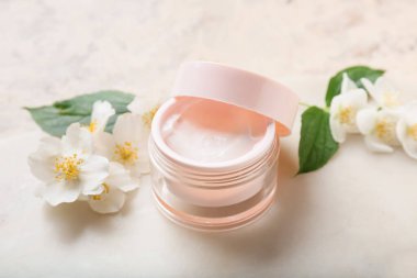 Hafif arka planda bir kavanoz krema ve yasemin çiçeği