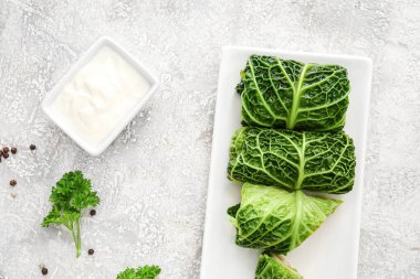 Doldurulmuş lahana yapraklı tabak ve açık arkaplanda ekşi krema.