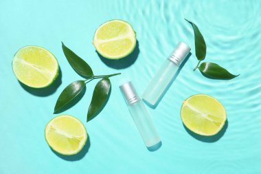 Renkli arkaplanda bir şişe parfüm, kireç ve yeşil yapraklar.