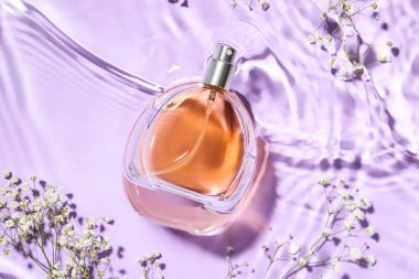 Renkli arka planda bir şişe parfüm ve çiçek, yakın plan.