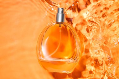 Renkli arka planda suda bir şişe parfüm, yakın plan.