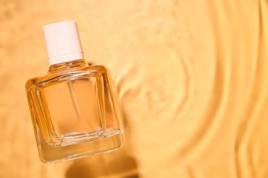 Renkli arka planda suda bir şişe parfüm.