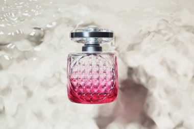 Hafif arka planda suda bir şişe parfüm.