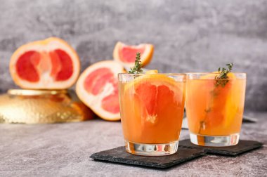 Gri arka planda bir bardak lezzetli greyfurt suyu.