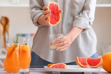 Mutfakta greyfurt sıkan kadın.