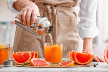 Mutfaktaki ışıklı masaya greyfurt suyu döken kadın.