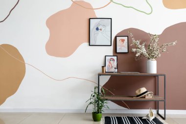 Çiçek açan dalları olan vazolar ve renk duvarına yakın resimler.