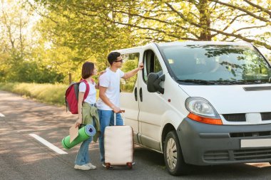 Genç çift yolda otostop çekiyor.
