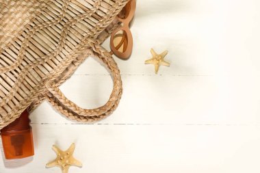 Güneş gözlüklü çanta ve açık ahşap arka planda güneş kremi.