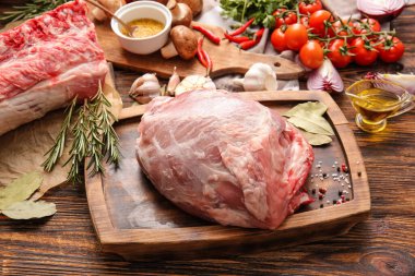 Ahşap arka planda çiğ domuz eti, baharat ve sebzeli pano.