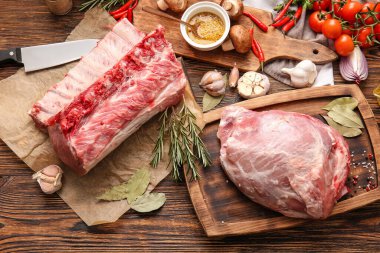 Ahşap arka planda çiğ domuz eti, baharat ve sebze.