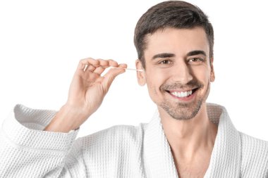 Beyaz arka planda pamuk tomurcuğuyla kulakları temizleyen genç adam.