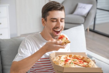 Genç adam evde lezzetli pizzalar yiyor.