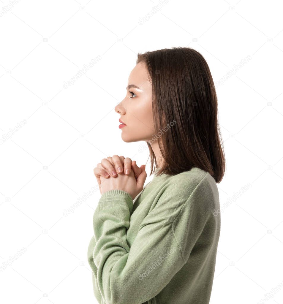 Religious young woman praying on white background