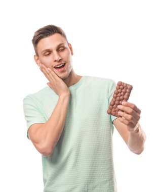 Beyaz arka planda lezzetli çikolataları olan şaşırmış genç bir adam.