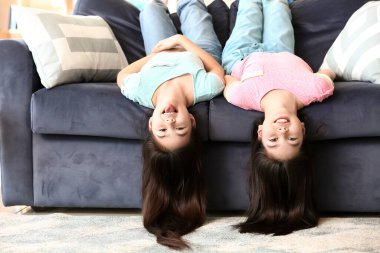Şirin Asyalı kız kardeşler evdeki kanepede eğleniyorlar.