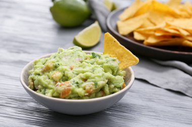Lezzetli guacamole ve ahşap arka planda nachos ile kase