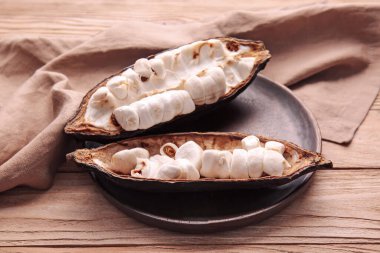 Ahşap zemin üzerinde taze kakao meyvesi olan bir tabak.