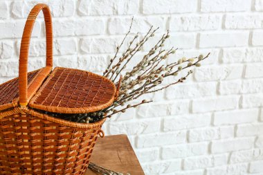 Tuğla duvarın yanındaki masada söğüt dalları olan sepet