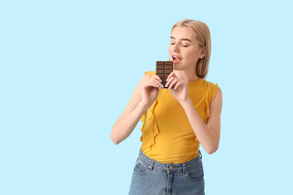 Beautiful Young Woman Eating Tasty Chocolate Color Background — Stock Photo, Image