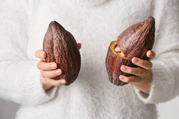Woman holding fresh cocoa fruits, closeup