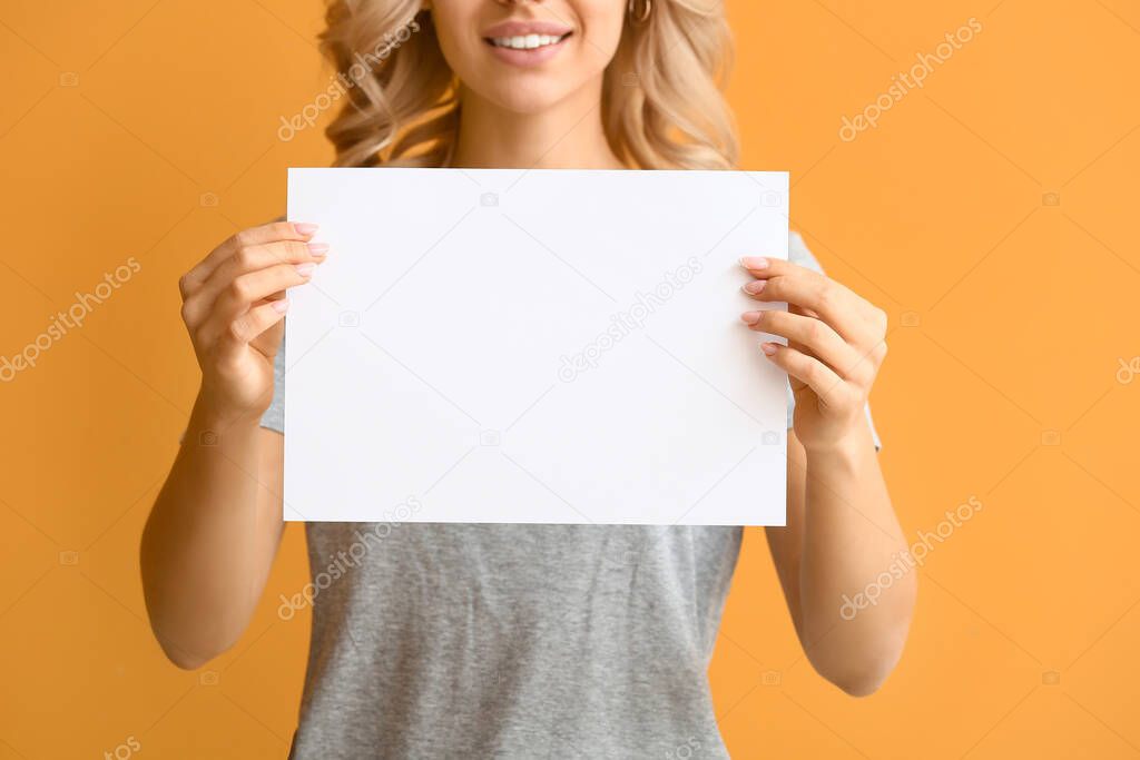 Young woman with blank paper sheet on color background
