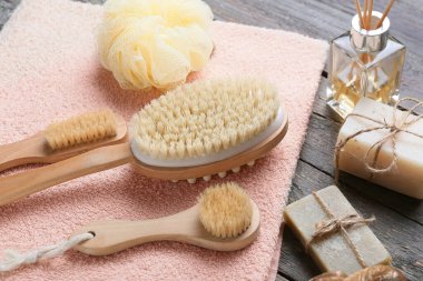 Tahta arka planda farklı masaj fırçaları ve banyo malzemeleri.