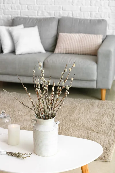 Oturma odasının içinde söğüt dalları olan bir vazo.