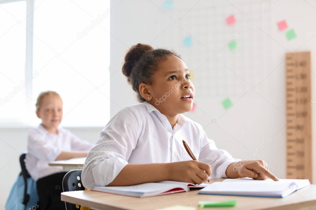 Cute African-American girl during lesson at school