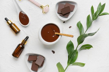 Gerekli yağ şişeleri, yüz masajı aleti ve hafif arka planda erimiş çikolata bileşimi