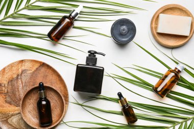 Hafif arkaplanda farklı kozmetik ürünler ve palmiye yaprakları