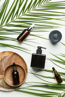 Hafif arkaplanda farklı kozmetik ürünler ve palmiye yaprakları
