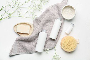 Hafif arka planda banyo malzemeleri ve çiçekler.