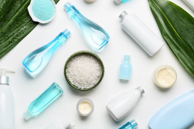 Hafif arka planda farklı kozmetik ürünleri ve deniz tuzu