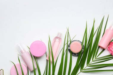 Farklı kozmetik ürünleri ve arka planda palmiye yaprağı içeren kompozisyon