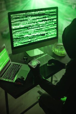 Hacker karanlık odada bilgisayar kullanıyor.